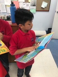 Boy reading a new book provided by Read with Me Volunteers